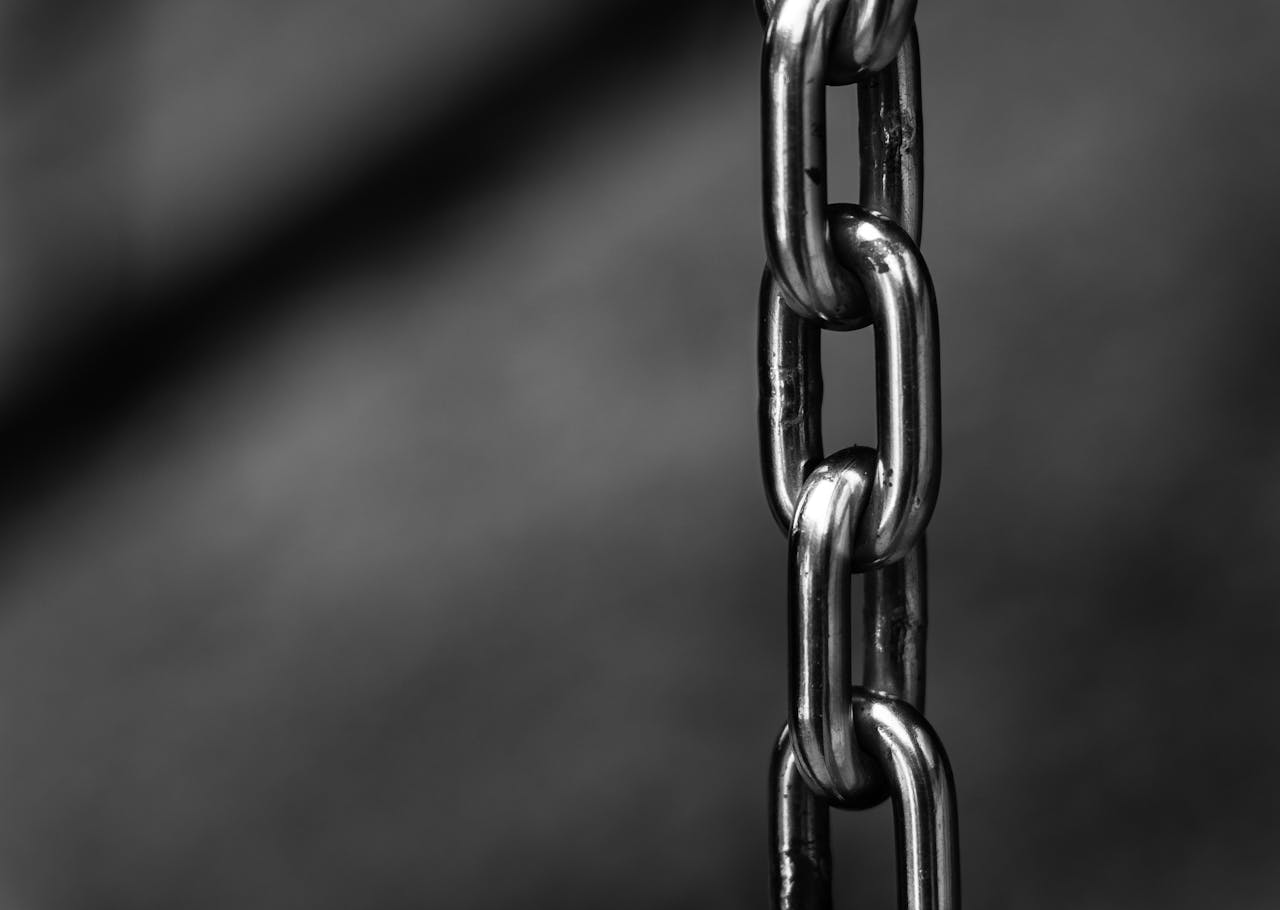 about-02 Detailed close-up of a strong shiny metallic chain link against a blurred background, emphasizing security.